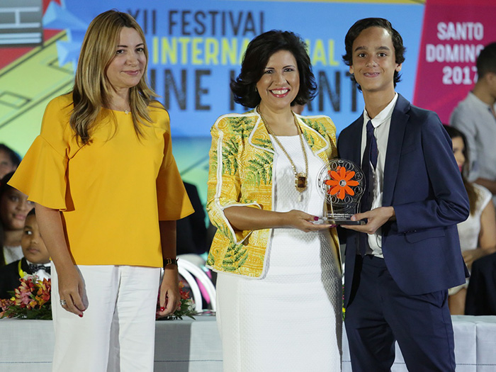 La vicepresidenta Margarita Cedeño entrega reconocimiento al actor estadounidense de origen dominicano Jaden Michael, conocido por participar en la película “Wonderstruck” de Amazon Films. Le acompaña la directora del Festival Internacional de Cine Infantil (FICI), Isabel Turull. (Foto de archivo).