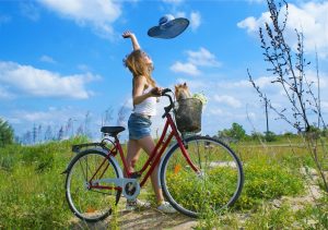 linda-chica-disfruta-un-día-soleado-a-orillas-de-la-ciudad-con-mascota-en-la-bicicleta